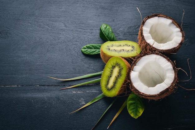 Noci di cocco e kiwi su un fondo di legno. Frutta e noci tropicali. Vista dall'alto. Spazio libero per il testo.