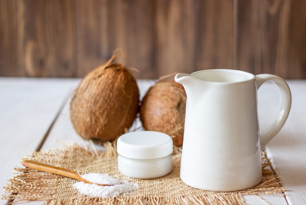 Noci di cocco e latte di cocco in una pentola di metallo. Fondo in legno