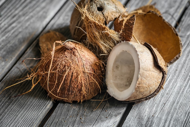 Noci di cocco fresche rotte sulla tavola di legno