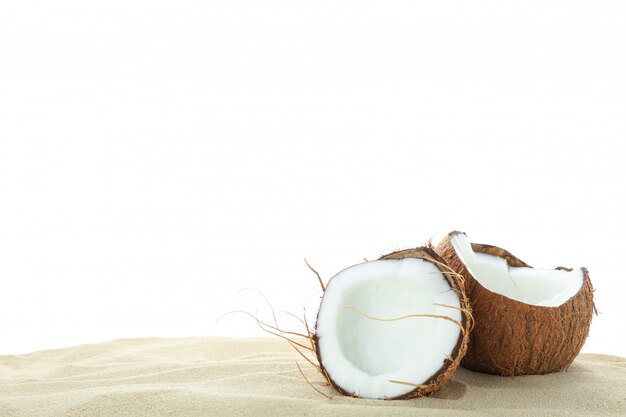 Noci di cocco su chiara sabbia di mare isolata su fondo bianco. Vacanze estive