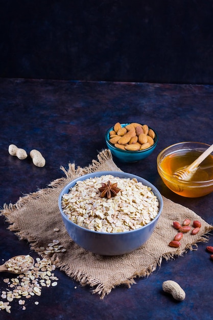 Noci di farina d'avena secca e miele Farina di avena e noci di mandorle su sfondo scuro Cereali e arachidi