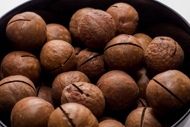 Noci di macadamia intere in banda nera. Spuntino vegetariano sano. Foto ravvicinata. Dieta vegetale.