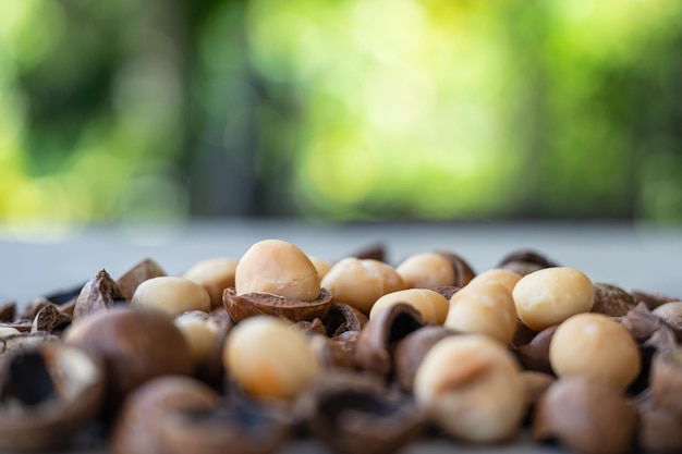 Noci di macadamia organiche e coperture sulla tavola di legno nel giardino