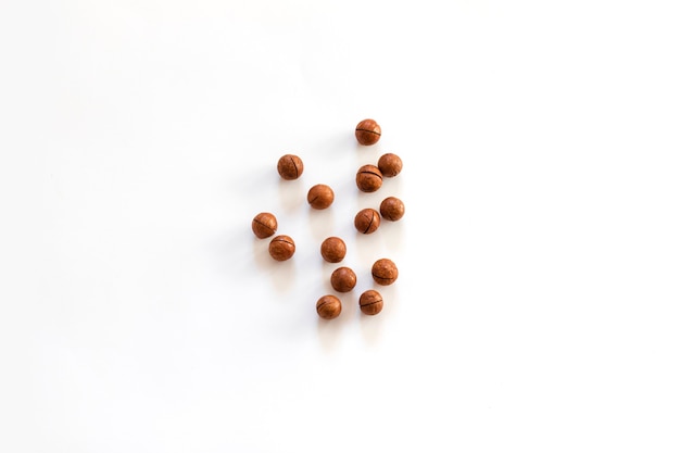 Noci di macadamia organiche e spazio per il testo su sfondo bianco, vista dall'alto, piatto laici