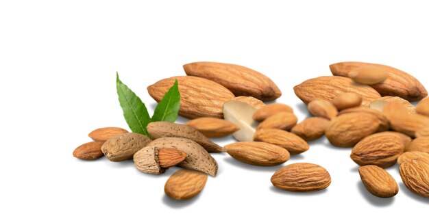 Noci di mandorle biologiche e foglie verdi su sfondo bianco Snack sano