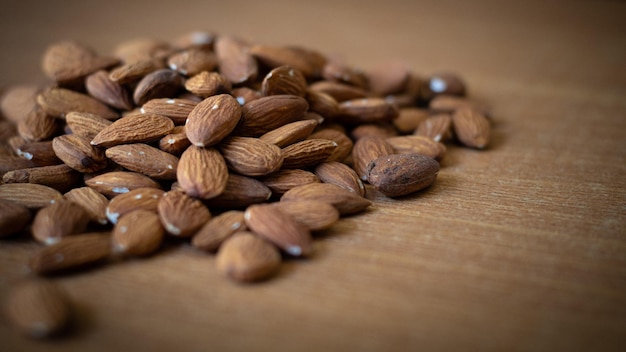 Noci di mandorle biologiche su tavola di legno fuoco selettivo vista dall'alto Spuntino sano Delizioso primo piano di noci di mandorle dolci tostate