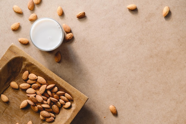 Noci di mandorle su un piatto di legno fatto a mano e latte vegetale vegetariano su uno sfondo di carta kraft Vista dall'alto piatta