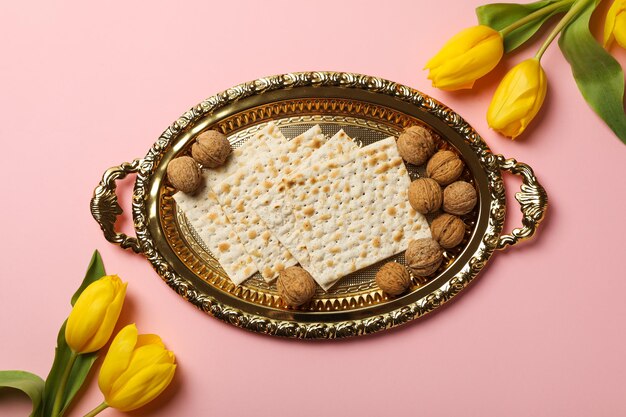 Noci di matzo e fiori su sfondo rosa vista dall'alto