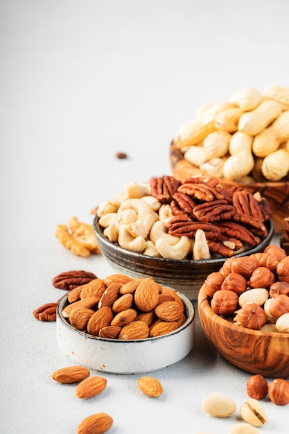 Noci in ciotole anacardi nocciole noci noci pecan mandorle e altro cibo sano snack mix sul tavolo grigio sfondo spazio copia