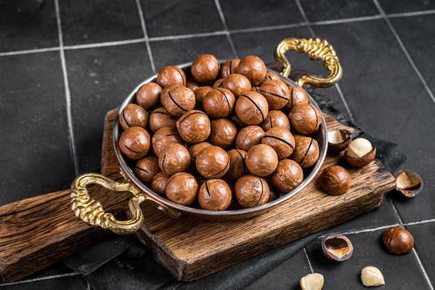 Noci macadamia in un guscio pronto da mangiare Sfondo nero Vista dall'alto