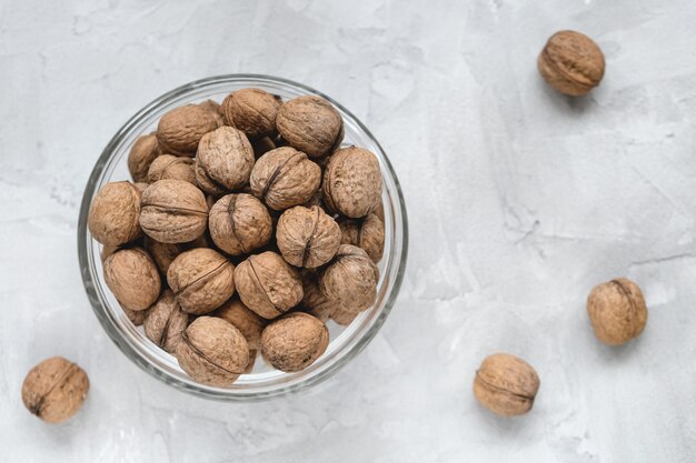 Noci non incrinate nelle coperture in ciotola sopra, concetto dell'alimento sano del vegano di cibo. Primo piano, messa a fuoco selettiva, copia spazio.