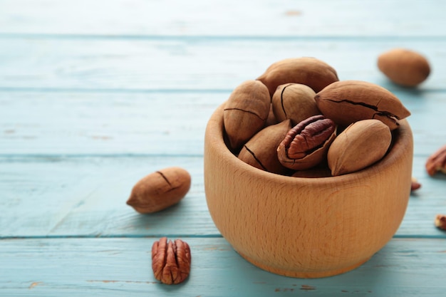 Noci pecan sulla ciotola di legno su fondo di legno blu