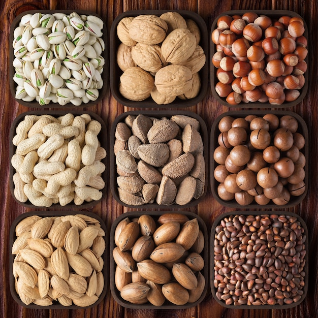 Noci sgusciate sulla tavola di legno del fondo. composizione salute alimentare: noci pecan, nocciole, noci, pistacchi, mandorle, macadamia, arachidi, pino, brasiliano.
