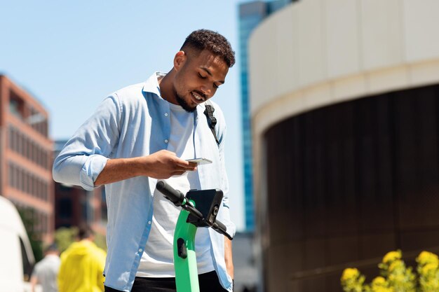 Noleggio di uno scooter elettrico giovane afroamericano che noleggia un mezzo di trasporto ecologico pagando online