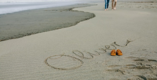 Nome del bambino scritto nella sabbia con le scarpe