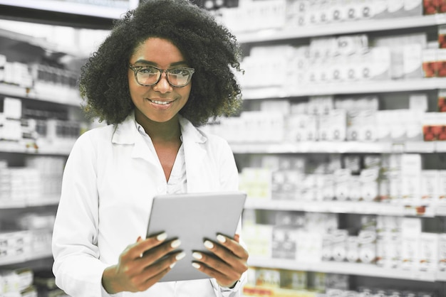 Non commettiamo errori Ritratto di una giovane farmacista allegra in piedi con una tavoletta digitale mentre guarda la fotocamera in una farmacia