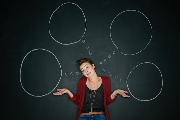 Non ho idea di cosa sto facendo Foto in studio di una giovane donna in posa con un'illustrazione in gesso di bolle di pensiero su uno sfondo scuro