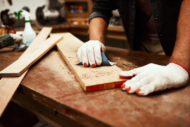 Non posso fare errori qui ora Primo piano di un falegname maschio irriconoscibile che esegue misurazioni su un pezzo di legno all'interno di un'officina di notte