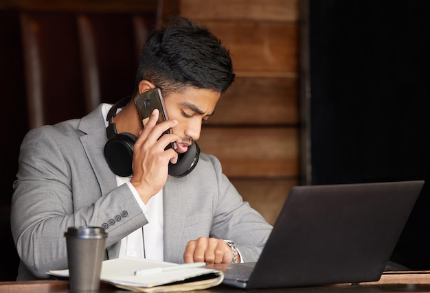 Non posso perdere questa telefonata d'affari davvero importante Foto di un giovane uomo d'affari che controlla l'ora mentre usa il telefono in un bar