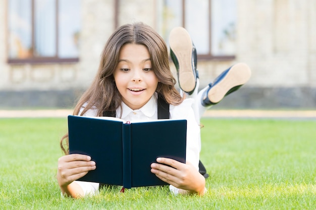 Non potrebbe esserci verità senza informazioni Il bambino piccolo ottiene informazioni dal libro della biblioteca Bambina sveglia che legge sull'erba verde Informazioni sulla scuola Istruzione e informazioni