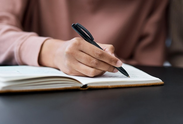 Non rinunciare mai ai tuoi obiettivi Inquadratura di una donna irriconoscibile che scrive su un taccuino mentre lavora da casa