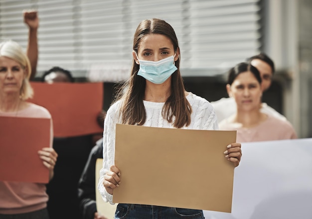 Non sarò controllato Ritratto ritagliato di una giovane donna attraente che indossa una maschera mentre partecipa a un comizio politico