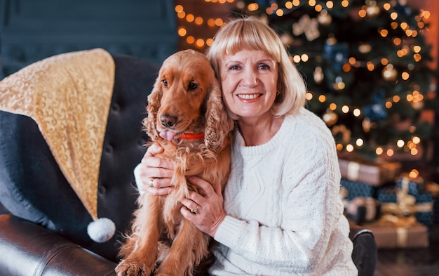 Nonna al chiuso con cane nella stanza decorata di natale.