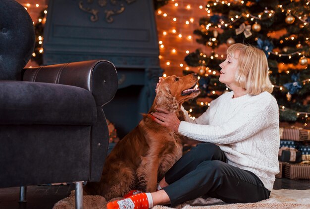 Nonna al chiuso con cane nella stanza decorata di natale.