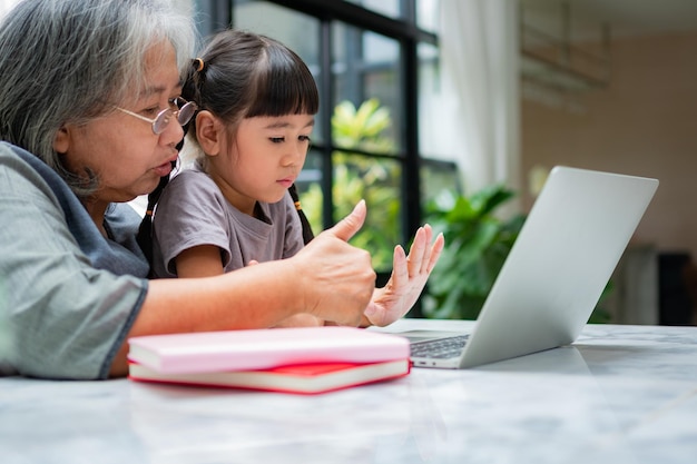 Nonna asiatica con i suoi due nipoti che si divertono e giocano a giochi educativi online