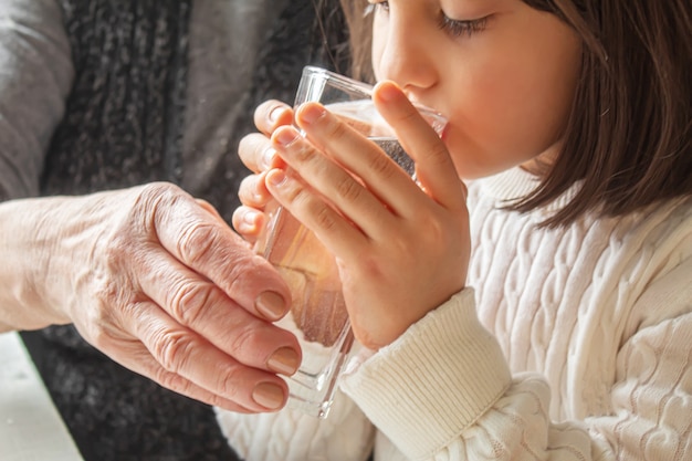 Nonna che dà un bicchiere di acqua pulita a un bambino. Messa a fuoco selettiva.persone