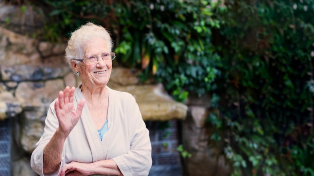 Nonna che saluta e sorride in un giardino