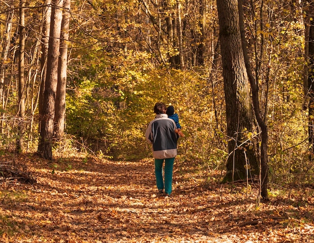 Nonna con suo nipote che cammina nella foresta d'autunno