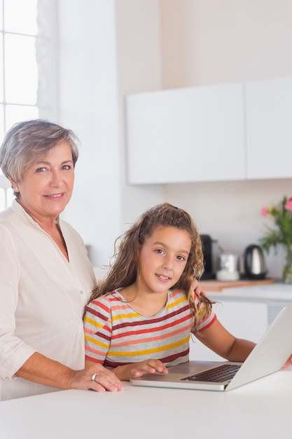 Nonna e bambino sorridenti che esaminano la macchina fotografica con il computer portatile