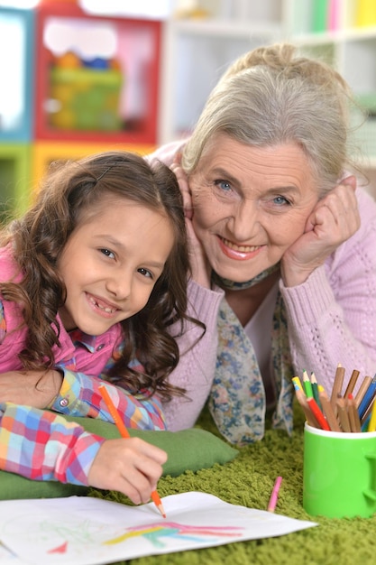 Nonna e nipote che si uniscono sdraiati sul pavimento a casa