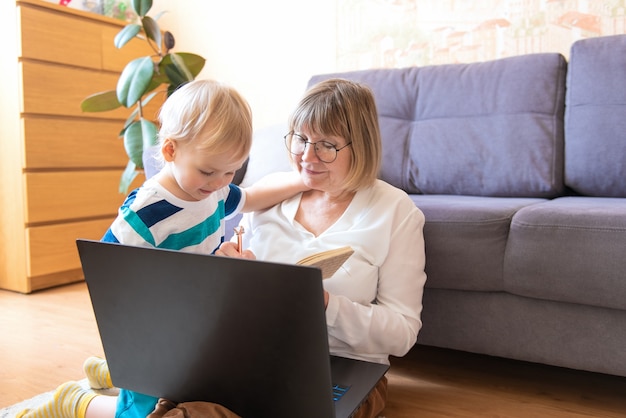 Nonna e nipote felici con laptop e notebook a casa