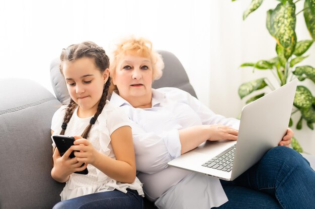 nonna moderna che insegna al nipote come utilizzare il computer portatile a casa.