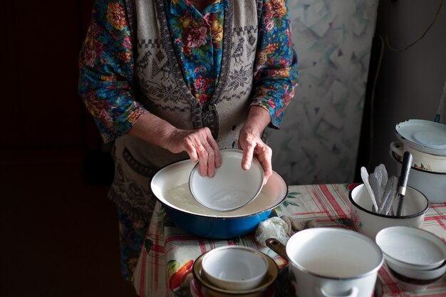 Nonna russa, lava i piatti, in una bacinella del villaggio.