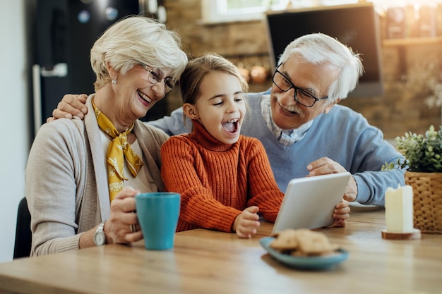 Nonni allegri e la loro nipote che navigano in Internet sul touchpad a casa