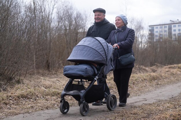 Nonni che camminano con un passeggino nel parco all'inizio della primavera