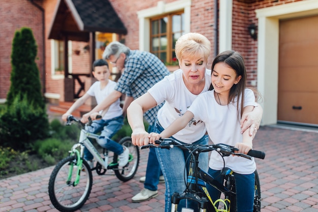 Nonni che insegnano a nipote e nipote ad andare in bicicletta..