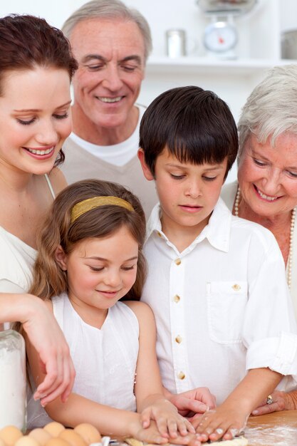 Nonni guardando i bambini che cuociono in cucina