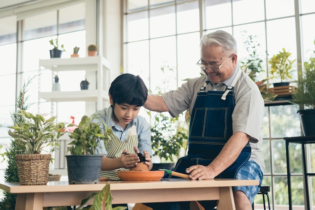 Nonno che fa giardinaggio e insegna al nipote prendersi cura delle piante