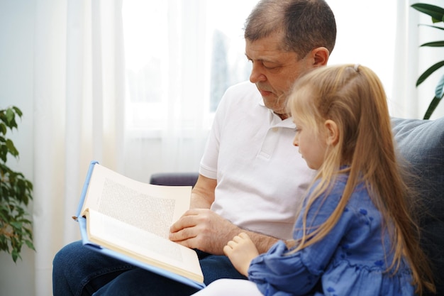 Nonno che legge un libro alla sua nipotina in soggiorno