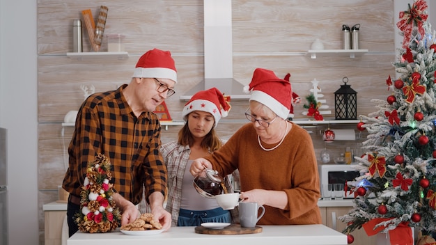 Nonno che serve bambino con un delizioso biscotto al forno mentre la nonna mette il caffè