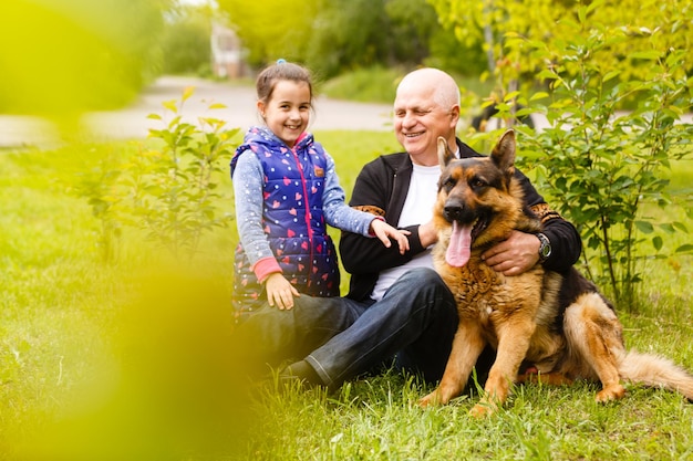 Nonno con la nipote e un cane in giardino