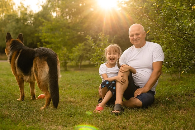 Nonno con la nipote e un cane nel giardino