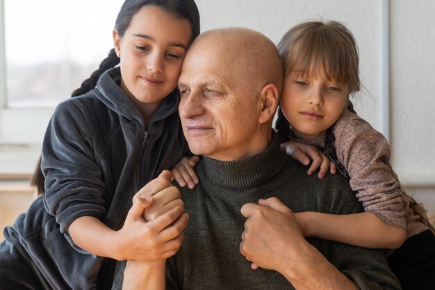 nonno e due nipoti che si abbracciano sul divano di casa.