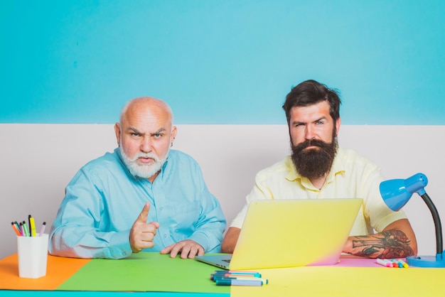 Nonno e figlio che lavorano con il computer portatile in ufficio vecchio padre e figlio che usano il taccuino