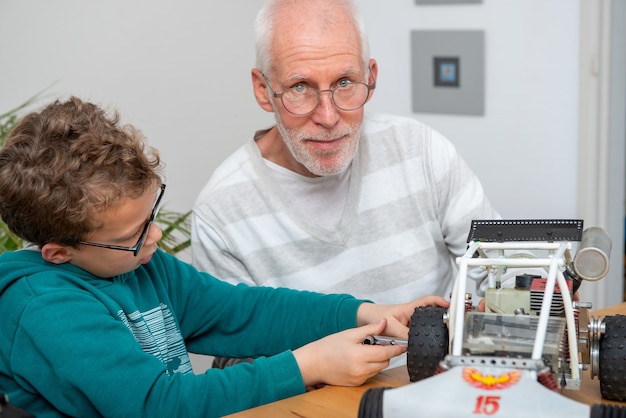 Nonno e figlio ragazzino che riparano un modello di automobile radiocomandata