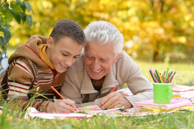 Nonno e nipote che disegnano insieme con le matite a tavola